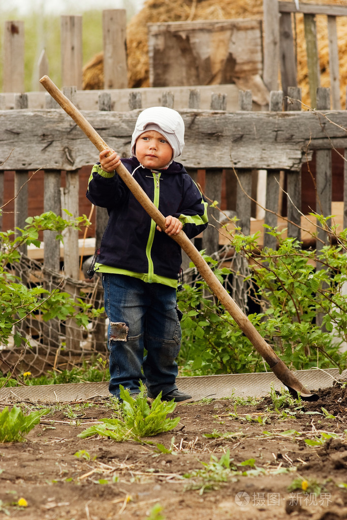 用铁锹在花园里的小男孩.乡村生活