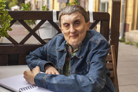 老年脑瘫残疾人在笔记本上写字。