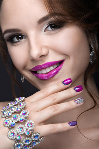 美丽的女孩与明亮的夜晚化妆和紫色指甲与莱茵石。 钉子设计。 美丽的脸。