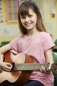 女孩在学校音乐课上学弹吉他