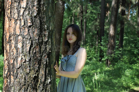 美丽的女孩，长发穿着连衣裙站在树附近