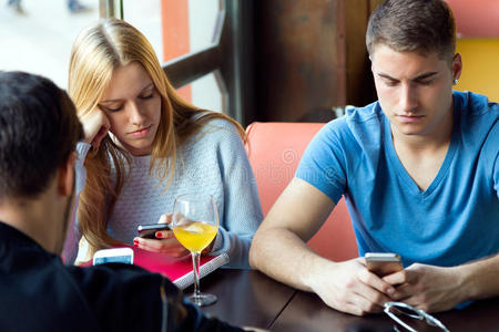 一群朋友在咖啡馆里用手机。