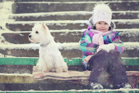 女孩玩白色狗冬天的雪