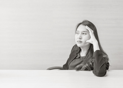 特写亚洲女人与思维面对情感上模糊的木桌, 木墙纹理背景在会议室内