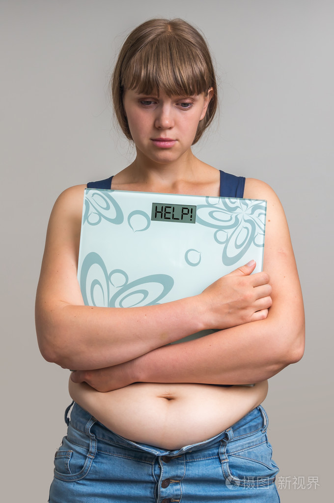 沮丧的超重妇女持有电子秤的帮助