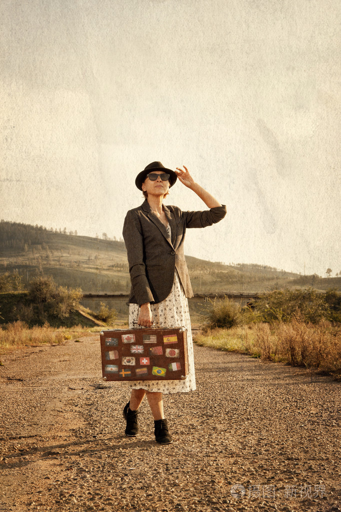 旧路上有老式手提箱的女人复古风格照片