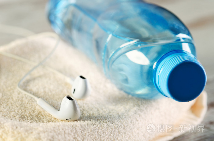白色耳机和一瓶水在毛巾上