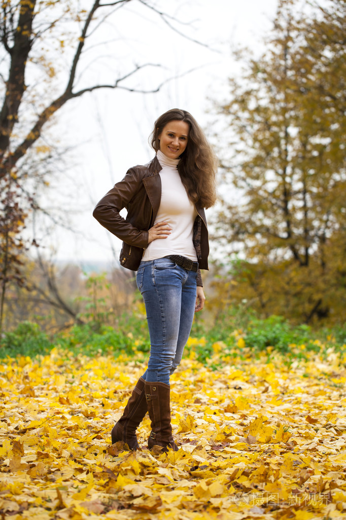 秋季时尚形象的年轻女子在公园散步
