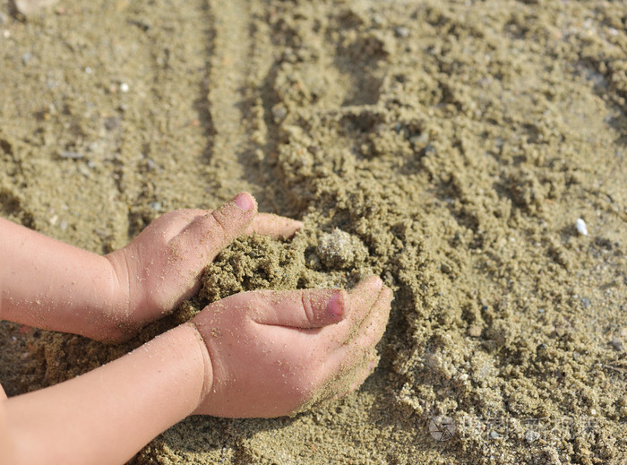 日落时孩子们在海滩上玩沙子开始建造一座城堡