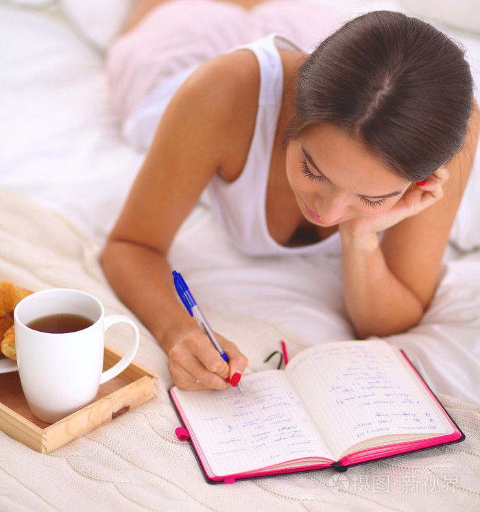 年轻漂亮的女人躺在床上写日记