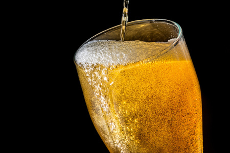 啤酒溢出泡沫与泡沫隔离在黑色背景上的大玻璃照片