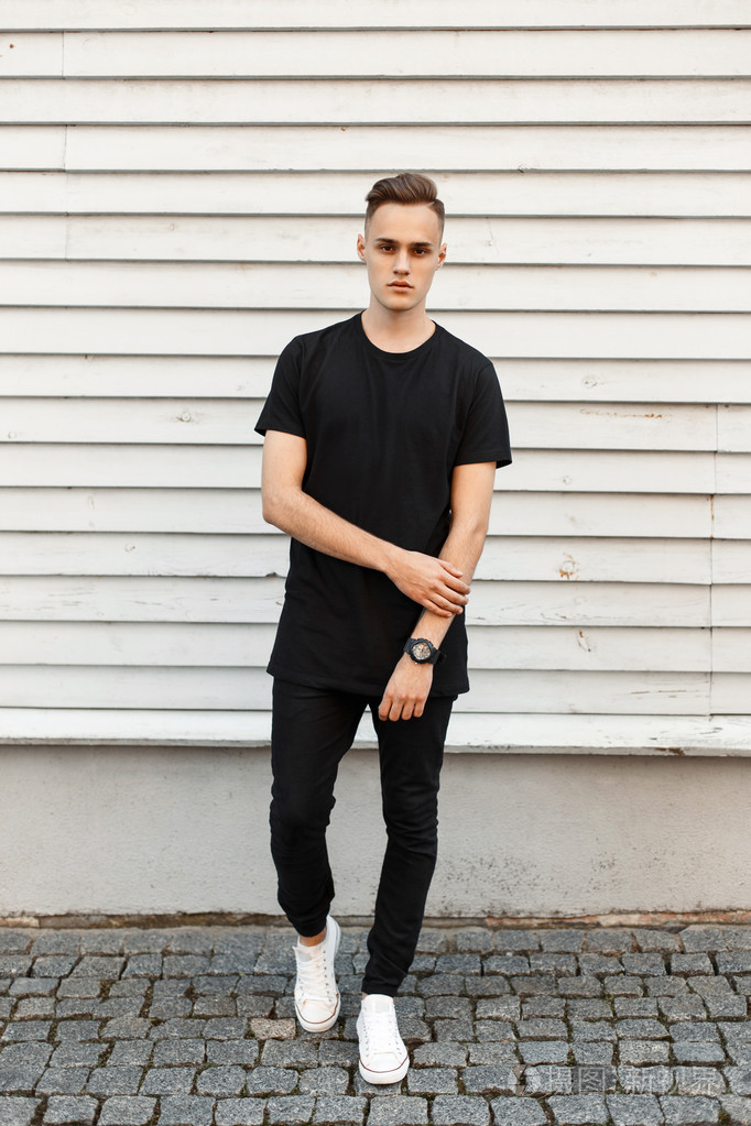 穿着黑色时髦连衣裙和白色运动鞋的年轻帅哥