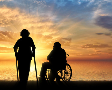 拐杖和老年男子坐在轮椅上的老妇人的剪影照片