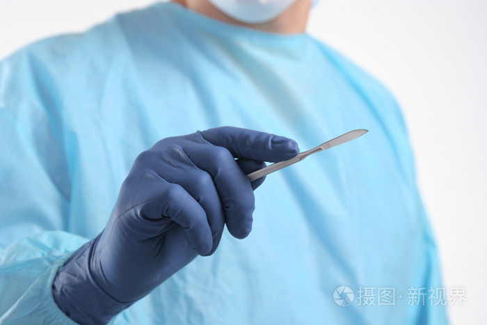在蓝色的外科医生男医生持有一把手术刀