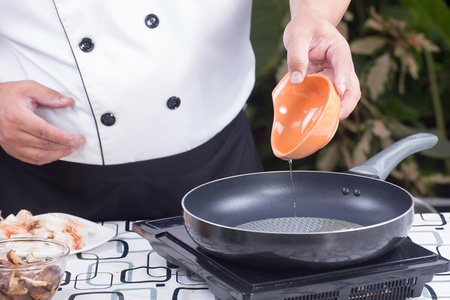 厨师把蔬菜油到锅里倒摄影图