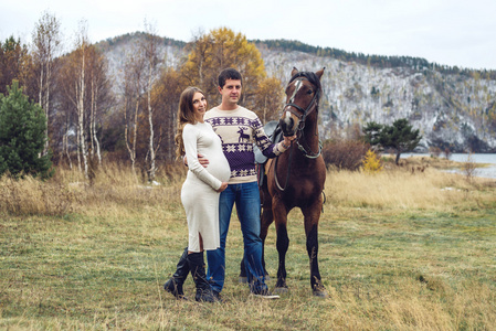 怀孕的女孩和她的丈夫站在马旁插画