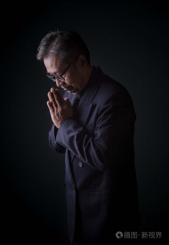泰国资深的人穿着黑色西装和祈祷与悲伤 em 的手
