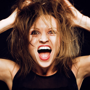 愚蠢的脸年轻的愚蠢的疯狂女孩,头发乱糟糟的,做着愚蠢的脸照片