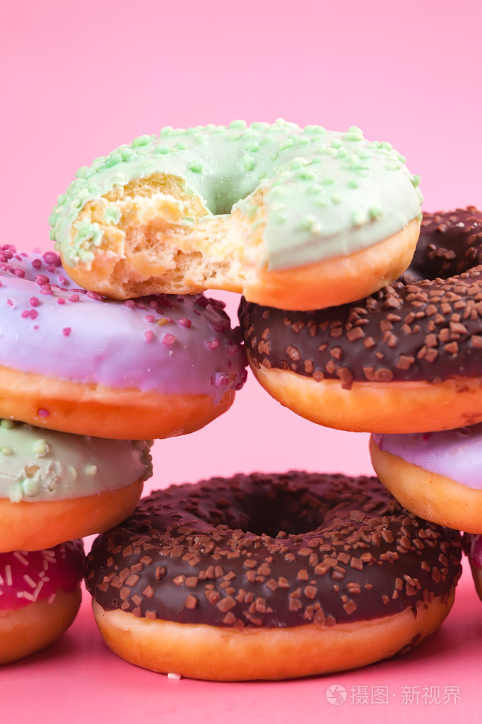 粉红色的背景上的甜蜜多彩美味甜甜圈