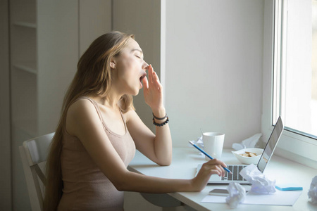 少妇被工人干有魅力的女人,打哈欠在笔记本电脑的侧面肖像照片