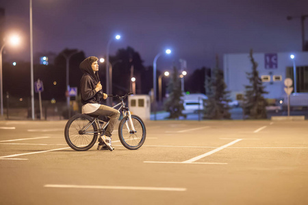 小男孩骑自行车在城里晚上照片