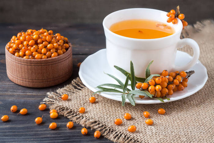 大果沙棘茶浆果与一枝上麻布和木制背景