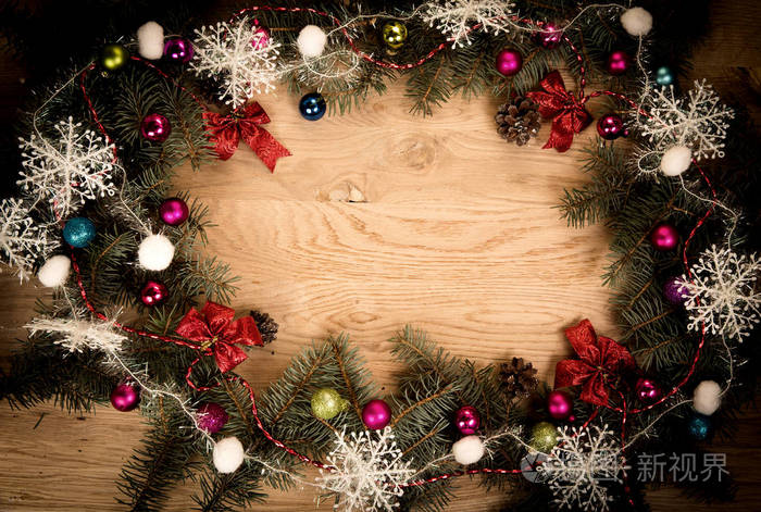 青翠的松树树枝与在圣诞装饰品的边缘变暗的木地板上