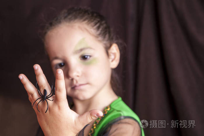 可爱的小女孩显示蜘蛛万圣节聚会前