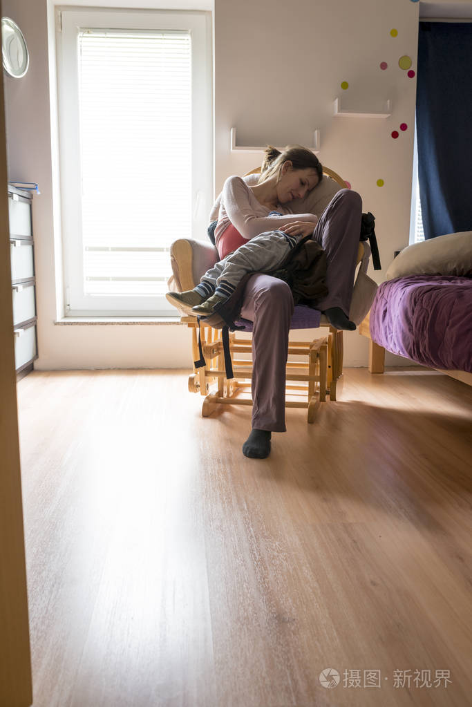 年轻妈妈坐着休息在摇椅上抱着她