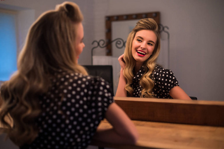 新发型可爱可爱的年轻女子在美容沙龙照照镜子照片