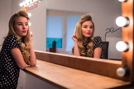 新发型可爱可爱的年轻女子在美容沙龙照照镜子照片