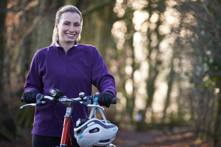女人骑山地自行车穿过树林图片