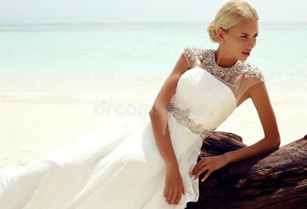 美丽的新娘穿着优雅的婚纱在热带海滩上摆姿势