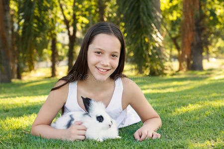 可爱漂亮的笑着的十几岁女孩和白色黑色的小兔子