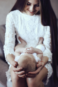 美丽的年轻母亲，长发黑发，与她的小可爱的婴儿摆姿势
