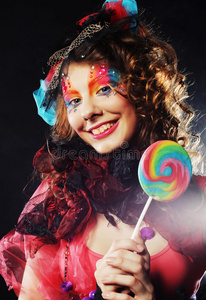 有创意化妆的女孩拿着棒棒糖。