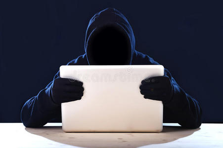 黑客男子在黑色引擎盖和面具与电脑笔记本电脑黑客系统在数字入侵者网络犯罪的概念