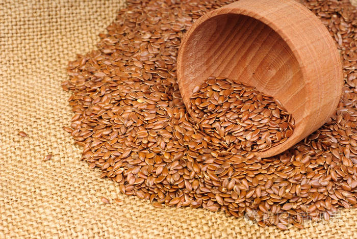 亚麻籽在一个木碗上画布背景