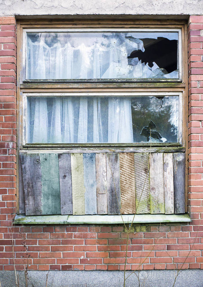 窗户在一个古老的红砖房子里被木板围起来