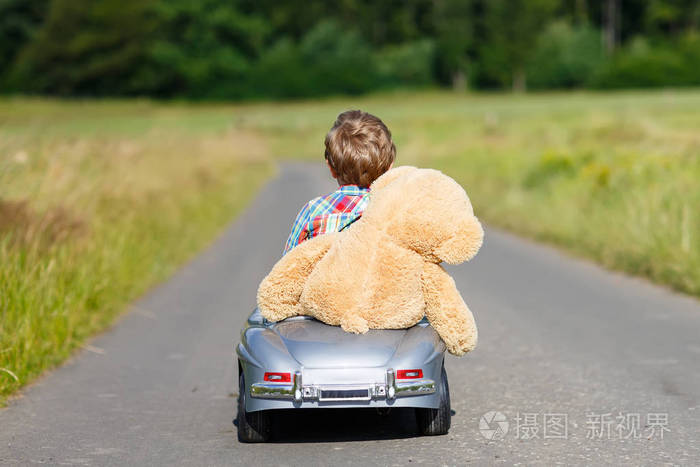 开车的大玩具和一只熊,在户外的小小孩男孩