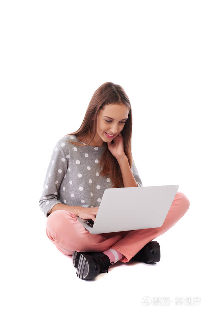 快乐的休闲女孩坐在地板上使用拉的侧视图