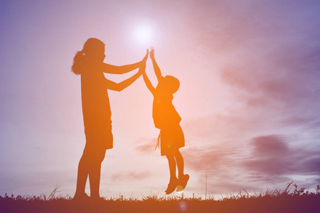 剪影手母亲和儿子上日落背景妈妈玩着她的儿子在山和高的剪影母亲和