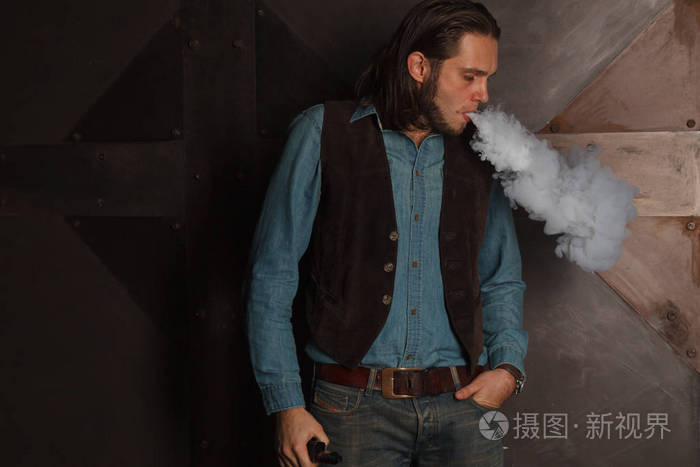 时尚的男人,用长长的头发吸烟电子烟
