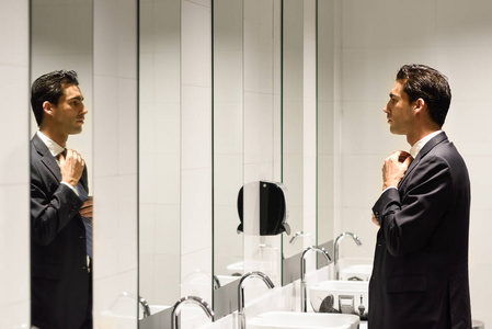 在公共厕所用镜子穿衣服的男人图片