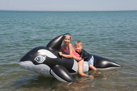 儿童漂浮在充气的虎鲸,密歇根湖,美国印第安那州沙丘照片