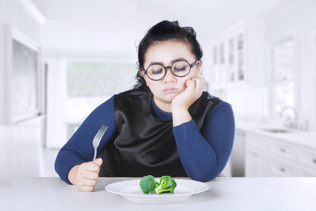 肥胖的女人感到厌倦与花椰菜图片