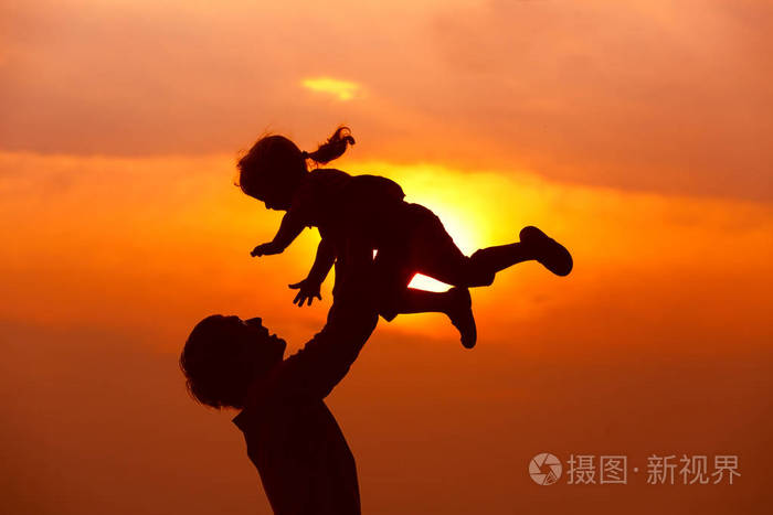 父亲和小女儿剪影发挥在日落时分
