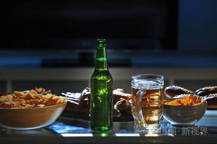 美味的小吃和模糊背景的厨房桌子上的啤酒