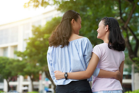 拥抱的可爱亚洲姐妹拥抱到户外散步的女孩照片
