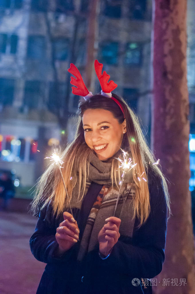 年轻的微笑着的女孩她手里拿着烟火女孩带亮片的特写